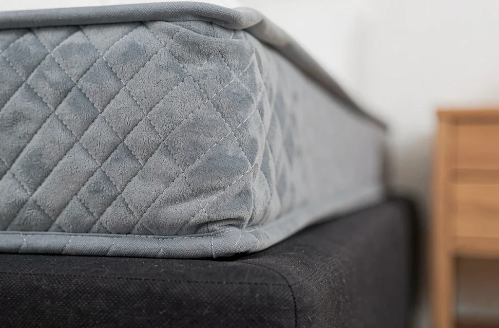Gros plan sur le coin d'une housse matelassée bleue fixée sous le matelas d'un clic clac